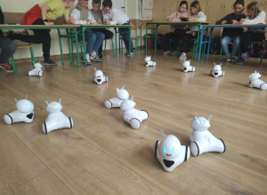 Białe, małe roboty edukacyjne o zaokrąglonym kształcie i świecących diodach.