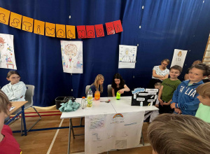 Dwie dziewczynki prezentują doświadczenie zatytułowane „Eksperyment rozkwitający kwiat”.