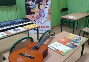 Na ławce szkolnej leży gitara i podręczniki z nutami.