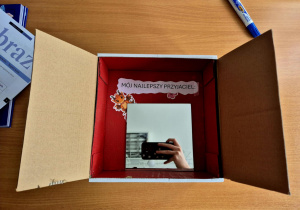 Pudełko z okienkiem, w którym ukryty jest napis "Mój najlepszy przyjaciel:" oraz lusterko.