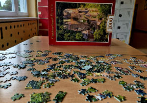 Prawie dokończone puzzle z motywem z filmu "Harry Potter" leżące na specjalnie przygotowanej ławce.