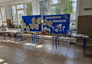 Szkolne ławki z wyłożonymi na nich książkami i dekoracja wydarzenia z napisem Niezwykłe książki.