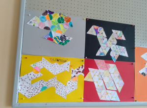 Prace uczniów z 6b przypięte do tablicy dekoracyjnej na korytarzu szkolnym.