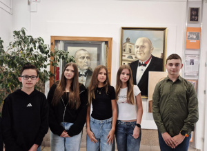 Skład Samorządu Uczniowskiego pozujący do wspólnego zdjęcia przy obrazie patrona szkoły.