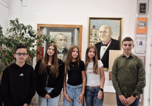 Skład Samorządu Uczniowskiego pozujący do wspólnego zdjęcia przy obrazie patrona szkoły.