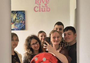 Opiekunka Samorządu Uczniowskiego, pani Kinga Blachowska oraz uczniowie zapozowali do wspólnego zdjęcia w lustrze z balonem w kształcie muchomora.