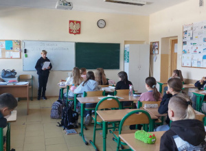 Uczniowie klasy 5a słuchają tekstu wiersza czytanego przez kolegę z ich klasy.