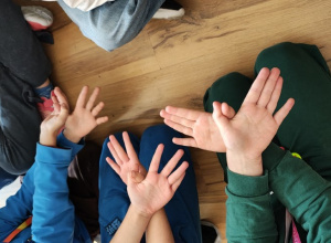 Dłonie uczniów migających słowo "motyl".