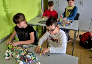 Zdjęcie czwórki dzieci z klasy 4B pracujących nad swoimi budowlami.