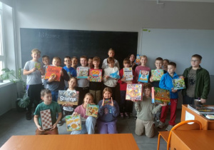 Grupa uczniów z klasy 4 b pozują z ulubionymi grami planszowymi.