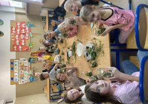 Uczniowie prezentują słoiki wypełnione ogórkami i dodatkami do kiszenia.