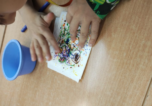 Uczeń moczy swoją pracę w celu rozmycia kolorów.