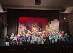 Uczniowie klas 4. stoją na scenie w teatrze.