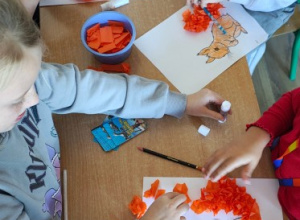 Uczniowie tworzą prace plastyczne z bibuły.