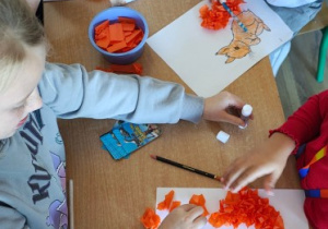 Uczniowie tworzą prace plastyczne z bibuły.