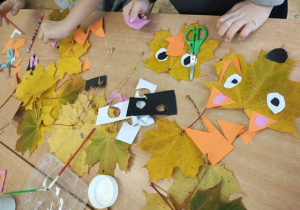 Uczniowie tworzą liski z liści i papieru.