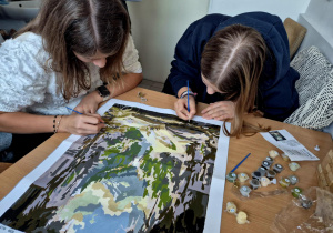 Dwie uczennice w skupieniu malujące obraz.