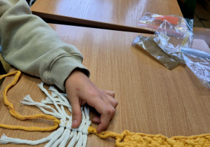 Biało-żółte makramy leżące na ławkach.