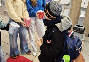 Chłopiec losuje karteczkę z pozytywną sentencją z kolorowego kubeczka.