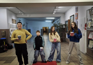 Czworo uczniów stoi na końcu czerwonego dywanu.