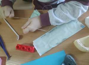 Uczennica w czasie nauki czyszczenia zębów nicią stomatologiczną.