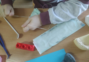 Uczennica w czasie nauki czyszczenia zębów nicią stomatologiczną.