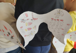 Kolorowe skrzydła prezentowane przez ucznia.