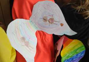 Kolorowe skrzydła prezentowane przez uczennicę.