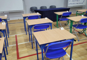 Sala gimnastyczna z przygotowanymi stolikami i krzesłami dla uczestników konkursu.