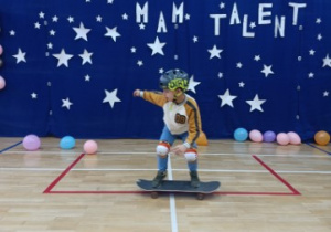 Pokaz umiejętności i trików na deskorolce w wykonaniu ucznia z klasy 1.