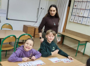 Dwoje uczniów klasy 1b pozują z wychowawcą do zdjęcia.