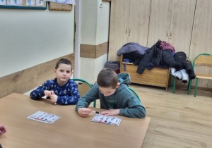 Dwaj uczniowie z mamą w trakcie zajęć z wykorzystaniem gier.