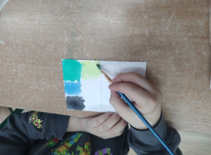 Uczennica maluje żółtą farbą.