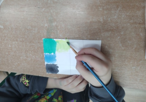 Uczennica maluje żółtą farbą.