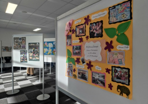 Pomarańczowy plakat na tle innych plakatów, przedstawiający działania podjęte w naszej szkole.