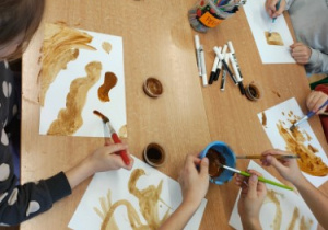 Uczniowie używają kawy do malowania.