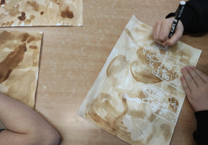 Białym markerem uczeń maluje kamienicę.