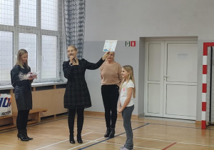 Uczennica klasy 3 z dumą odbiera dyplom i nagrodę.