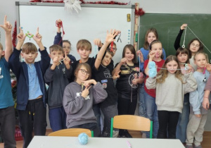 Uczniowie z klasy 4 a prezentują wykonane na warsztatach szydełkowych wisiorki i zawieszki.