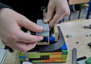 Chłopiec buduje domek z klocków LEGO na ławce.