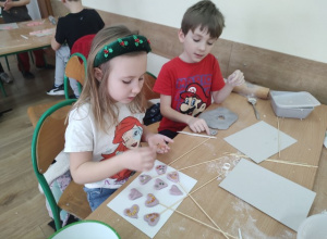 Dwoje uczniów ozdabia ulepione serduszka.