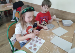 Dwoje uczniów ozdabia ulepione serduszka.