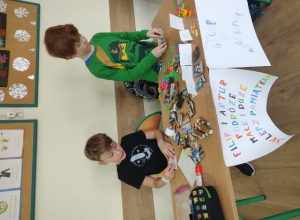 Uczniowie klasy 1b szykują wystawę sklepiku z pamiątkami.