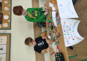 Uczniowie klasy 1b szykują wystawę sklepiku z pamiątkami.