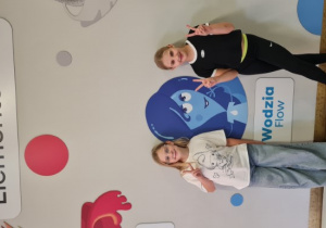 Dziewczynki stoją na tle tablicy Żywiołaki.