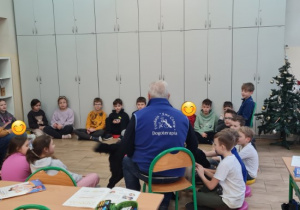 Dzieci wraz z nauczycielem i terapeutą oraz psami siedzą w kole na podłodze.