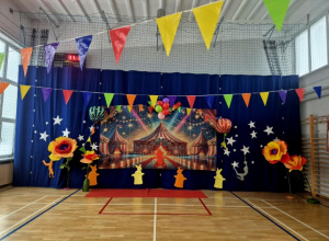 Kotara na sali gimnastycznej udekorowana w tematyce cyrku z wielkimi kwiatami stojącymi obok.