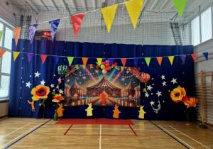 Kotara na sali gimnastycznej udekorowana w tematyce cyrku z wielkimi kwiatami stojącymi obok.