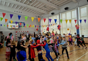 Dzieci bawiące się podczas balu karnawałowego na sali gimnastycznej.