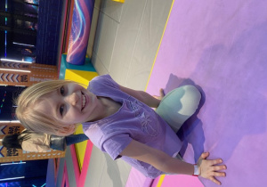 Uśmiechnięta uczennica skacze na trampolinie.